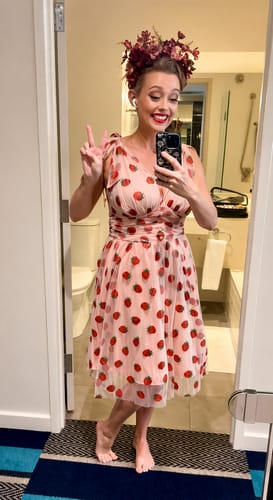 Reviewer taking a happy mirror selfie in the Pink 1950s Strawberry Mesh Swing Dress, showing its fit and full skirt.