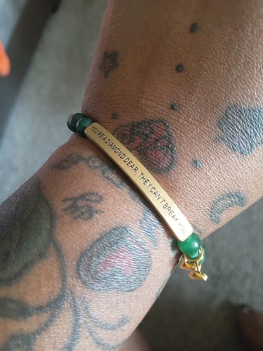 Reviewer wearing the gold-colored 'You Are a Diamond Dear' bracelet on their tattooed arm.