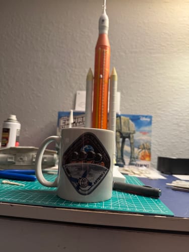 Reviewer's Artemis II mug displayed on a desk in front of a model rocket.