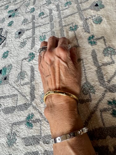 Reviewer showing a gold and silver Wave Bangle with Stones worn on their wrist.