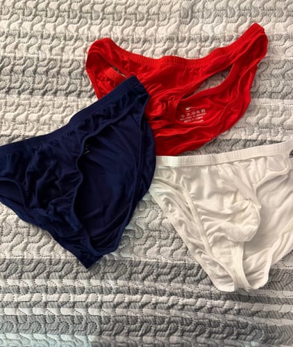 Customer's red, navy blue, and white Modal Bikini Briefs laid out on a bedspread.