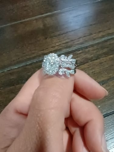 Reviewer's hand holding the sparkling platinum enhancer ring with a leafy design, shown with a central oval ring.