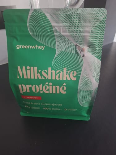 Un client montre le sachet de Milkshake protéiné saveur fraise sur une table.