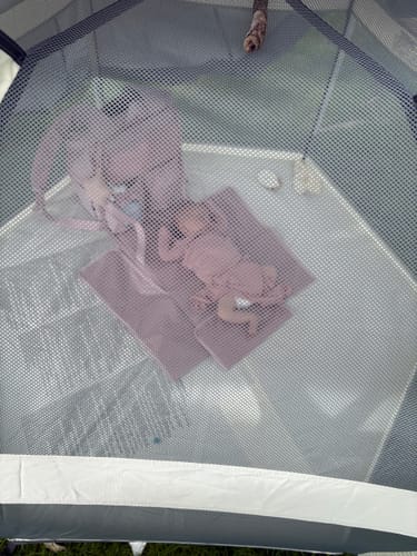 Customer's baby resting inside the grey Pop 'N Go Playpen, viewed from above through the protective mesh top.