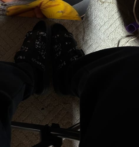 Reviewer wearing black Draco Socks with patterned black slides.