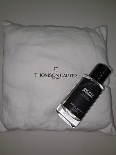Customer's Smoke & Mirrors Eau de Parfum bottle resting against its white branded cloth bag.