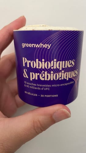 Main d'un client tenant le pot violet de Probiotiques & Prébiotiques contre un fond blanc.