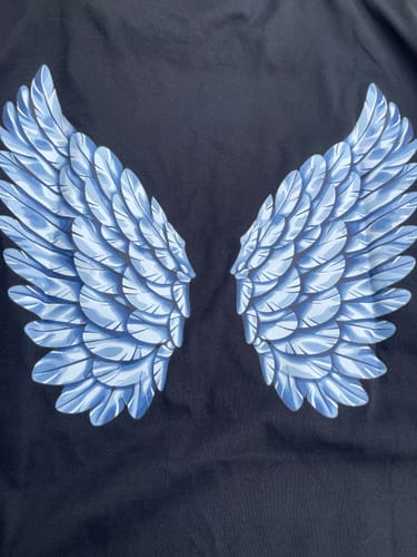 Gros plan d'un client sur le dos du T-shirt Ange, montrant les ailes bleues.