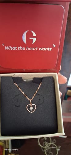 A reviewer's hand holding the open red GIVA box, showcasing the Rose Gold Your Lover Pendant with its link chain inside.