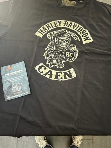 Photo d'un client du T-shirt Faucheuse HC noir, posé à plat pour bien montrer l'impression.