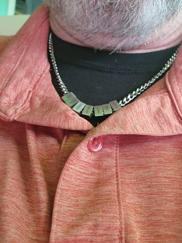 Close-up of a reviewer wearing the stainless steel Legacy necklace with name beads.