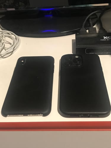 Reviewer's two iPhones in sleek, black MagCase Leather cases sitting side-by-side on a desk.