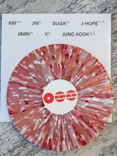 Customer's BTS ARIRANG deluxe vinyl. The reddish and white splatter record sits on a paper insert with the members' names.
