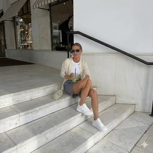 Reviewer sitting on outdoor steps wearing white Ortho Balance sneakers with a casual outfit.