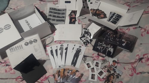 Customer's unboxed BTS Arirang 5th Album set, with photocards, keychains, and photo books spread across a bed.