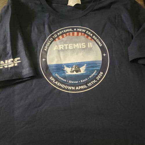 Customer's new Apollo To Artemis T-shirt in navy blue, laid flat showing the wrinkled fabric and full graphic.