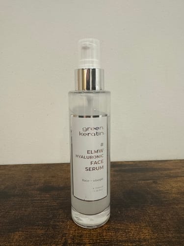 Client présentant le flacon du Sérum à l'acide hyaluronique ELMW sur une surface en bois.