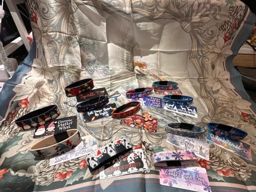 Reviewer's full collection of festive bracelets and cards from The Enchanted Mountain Advent Calendar displayed on a scarf.