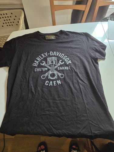 T-shirt Custom Garage noir d'un client, posé à plat sur une table pour montrer le graphisme.
