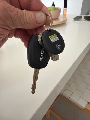 Customer holding a set of car keys with the black SmartTag attached to the keyring.