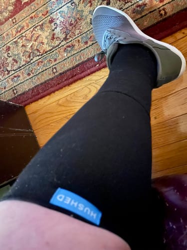 A reviewer's leg wearing a black Performance Eucalyptus Compression Sock with a grey athletic shoe.