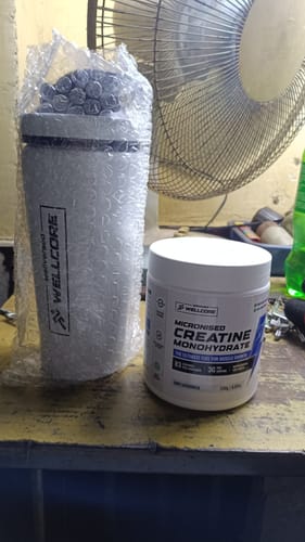 Customer's Wellcore Creatine Monohydrate tub and a shaker bottle on a yellow table.