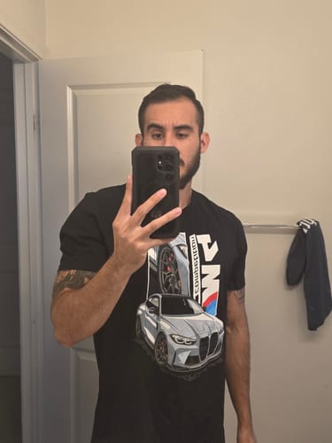 Reviewer in a mirror selfie wearing a black graphic tee from the TCG93 MYSTERY CASH BOX.