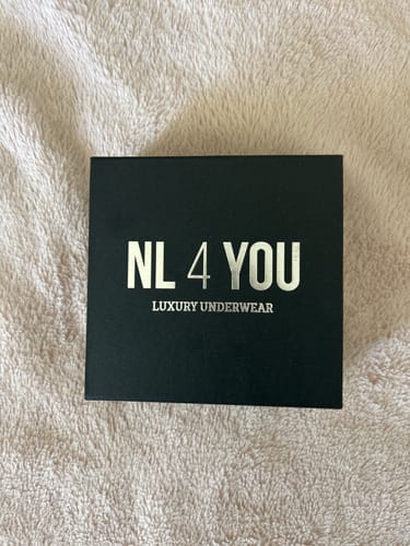 Клиентска черна луксозна кутия NL4YOU, поставена върху пухкава, светла повърхност.