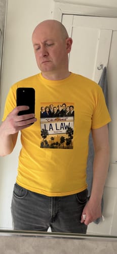 Customer taking a selfie in a yellow Summer t-shirt with a clear graphic print of the 'LA Law' show poster.