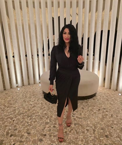 Reviewer posing in the black Natasa Long Sleeve Wrap Midi Dress, showing its V-neckline and front slit.