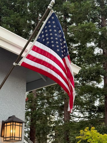 Customer's bronze Prestige House Flag Pole mounted on a house, displaying the American flag.