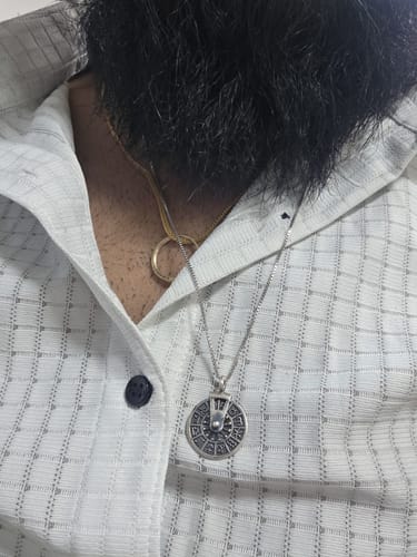 Reviewer wearing the Oxidised Silver Zodiac Spin Pendant with its box chain against a patterned shirt.