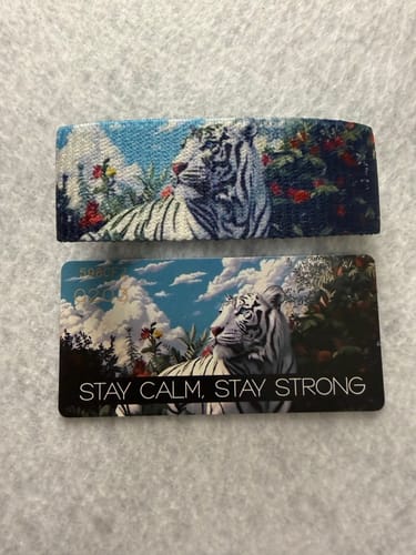 Reviewer's Stay Calm, Stay Strong Tiger Bracelet next to its matching collector's card with the same white tiger art.