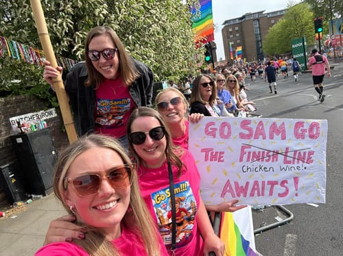 A group of customers wearing matching pink unisex t-shirts while cheering at the London Marathon.