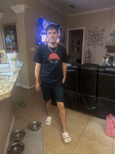 A customer stands in a living room wearing the black Statement Made t-shirt featuring a cat graphic.