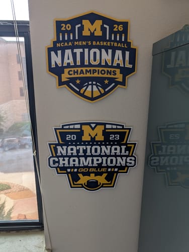 Reviewer's Michigan Basketball Champions wall art mounted on a wall above a similar football champions sign.