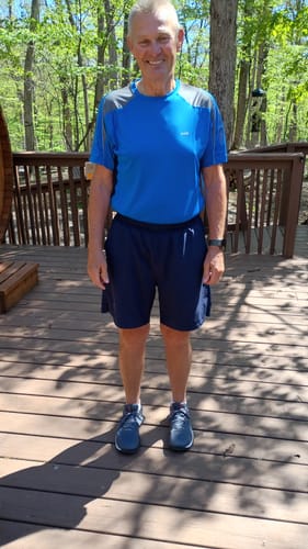Customer standing on a wooden deck wearing blue CUURT Muuv court shoes.