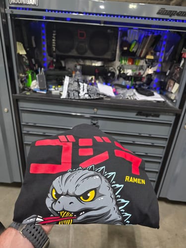 Customer holding the black RAMEN MONSTER TEE, showing the monster graphic and red Japanese text on the front.