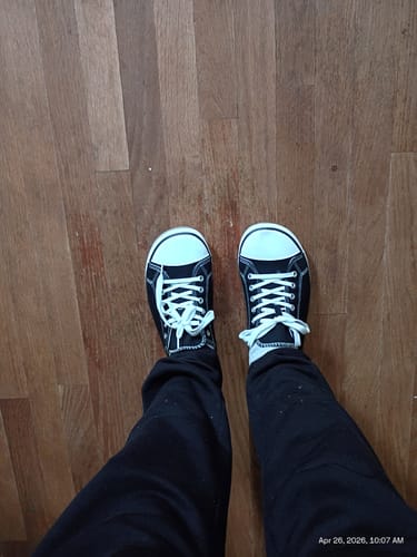 A reviewer's top-down view of their black Roam I - Barefoot Shoes on a wood floor.