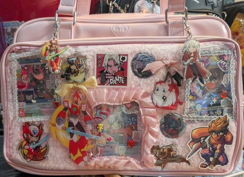 Customer's pink COKO STAGE BAG with its front display filled with colorful anime-style charms and pins.
