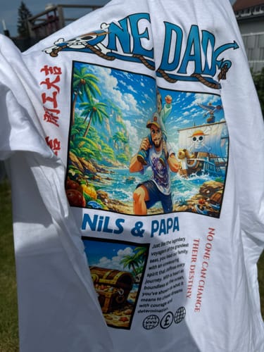 Kunde hält sein personalisiertes 'ONE DAD' T-Shirt mit einem farbenfrohen Aufdruck hoch.