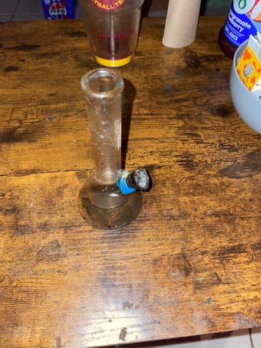 A customer's classic round beaker water pipe, appearing used, sitting on a wooden table.