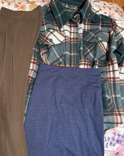 Customer shows the three items from their Mystery Bag: brown leggings, a navy skirt, and a plaid shaket.