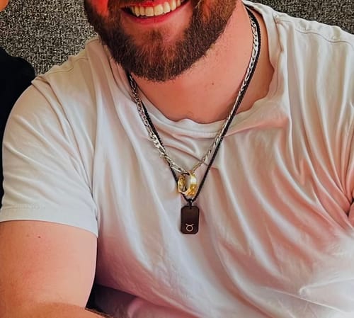 Reviewer wearing their personalized Matte Modern Dog Tag engraved with the Taurus zodiac symbol.