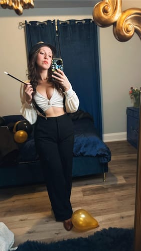 Reviewer dressed in a 1920s costume with suspenders and a fedora for the murder mystery game.