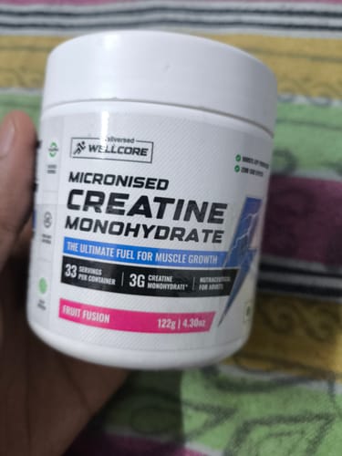 A customer holding the white tub of Wellcore Micronised Creatine Monohydrate in the Fruit Fusion flavor.