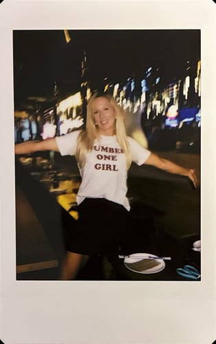 Reviewer wearing the white 'Number One Girl' t-shirt at night with arms outstretched.