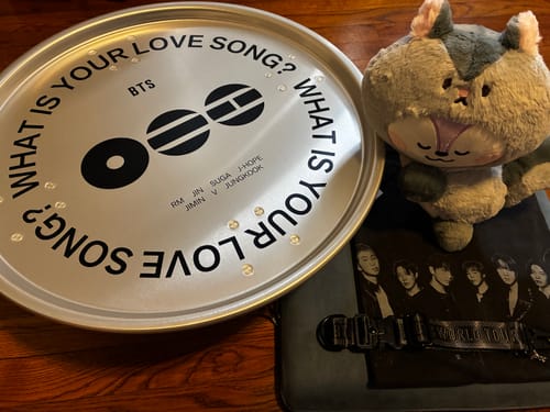 Customer's round, silver BTS Arirang MD table on a wooden surface with other merchandise.