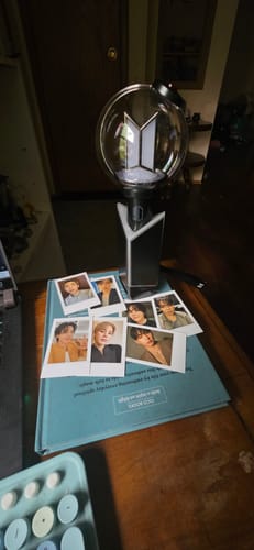 Reviewer's BTS Official Light Stick Ver.4 displayed with the included instant photos of the members on a wooden surface.