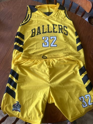 Customer's custom yellow and black basketball uniform set laid out, showing 'BALLERS' and the number 32 on the jersey and shorts.
